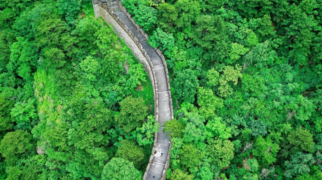 Drone view of the Great Wall of China winding through a verdant forest in Huairou, Beijing.