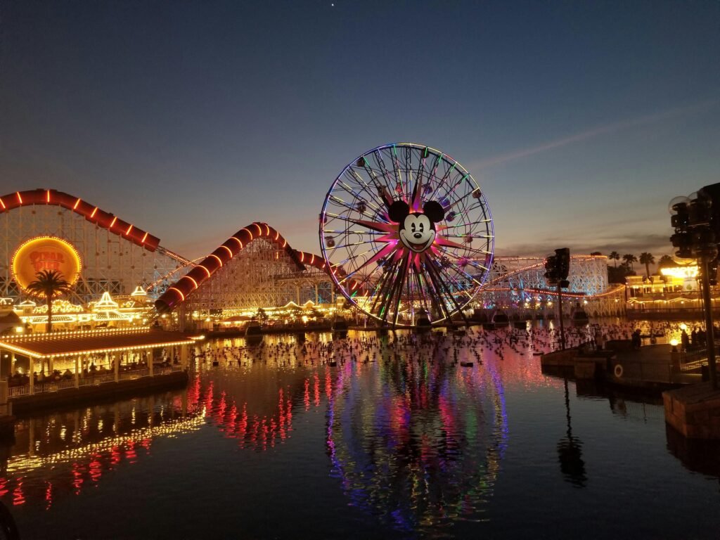 Lit-up Ferris wheel and roller coaster at Disneyland California Adventure during twilight.
