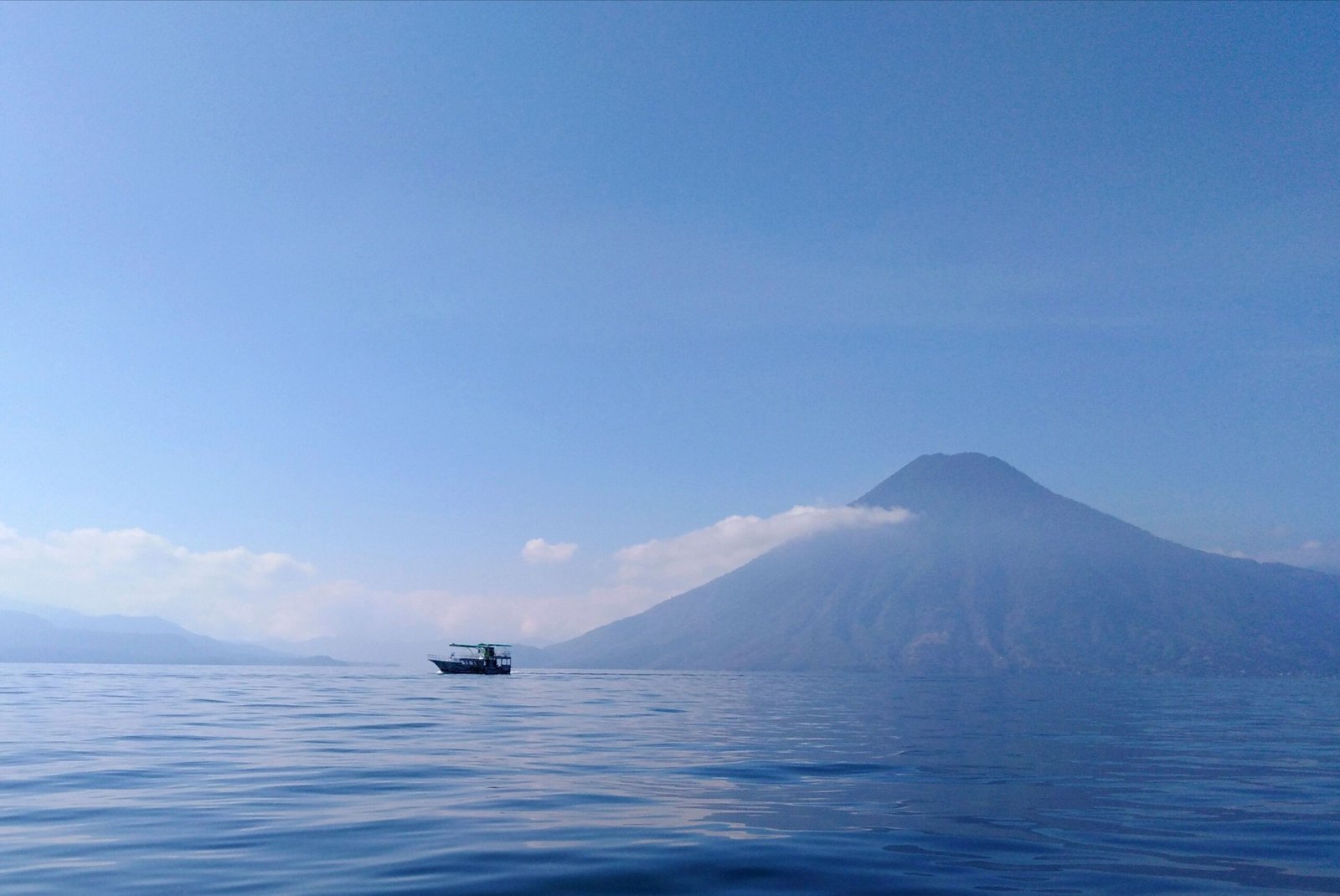 Guatemala Tranquil view of Lake Atitlán and volcano surrounded by clear blue sky, Sololá, Guatemala.